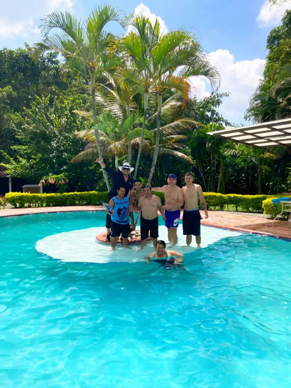 Grupo disfrutando la piscina de una finca campestre rodeada de palmas